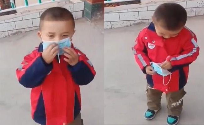 A cute little boy eating lollypop with face mask